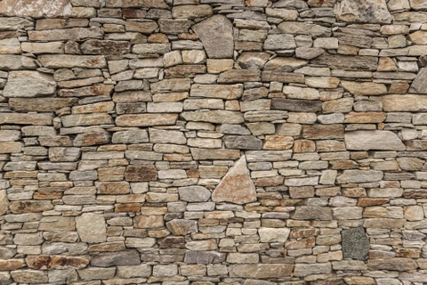 Mur en pierre sèche extérieur composé de moellons calcaires de tailles variées, assemblés sans mortier selon la technique traditionnelle de maçonnerie à pierres apparentes