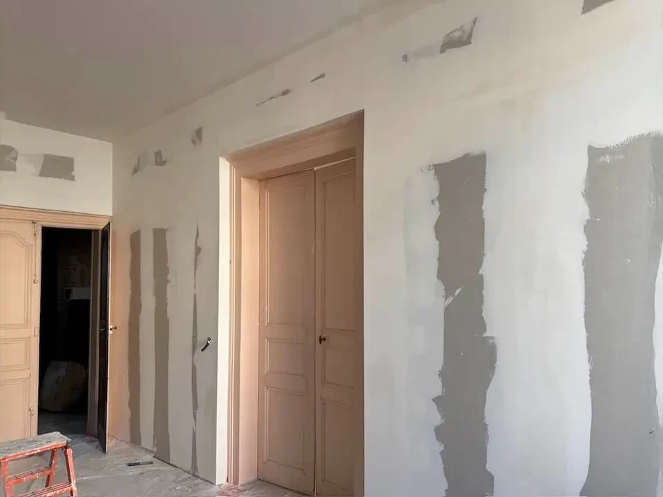 Ouvrier en bâtiment installant de l'isolant thermique en laine minérale jaune entre les montants d'une cloison intérieure