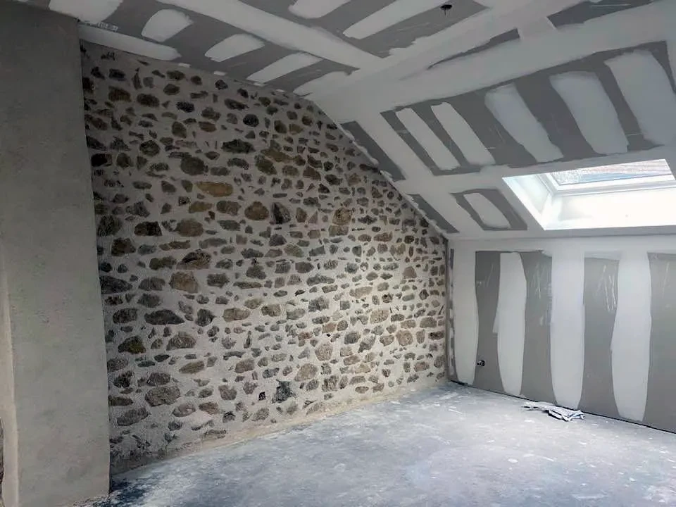 Cuisine moderne ouverte avec îlot central et quatre tabourets noirs, intégrée dans un espace de vie contemporain