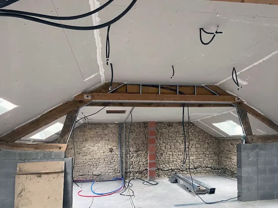 Intérieur de combles en cours d'aménagement avec charpente en bois apparente