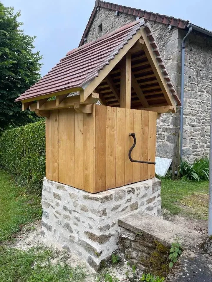 Façade d'une maison provençale en pierre naturelle avec volets verts, située sous un ciel bleu