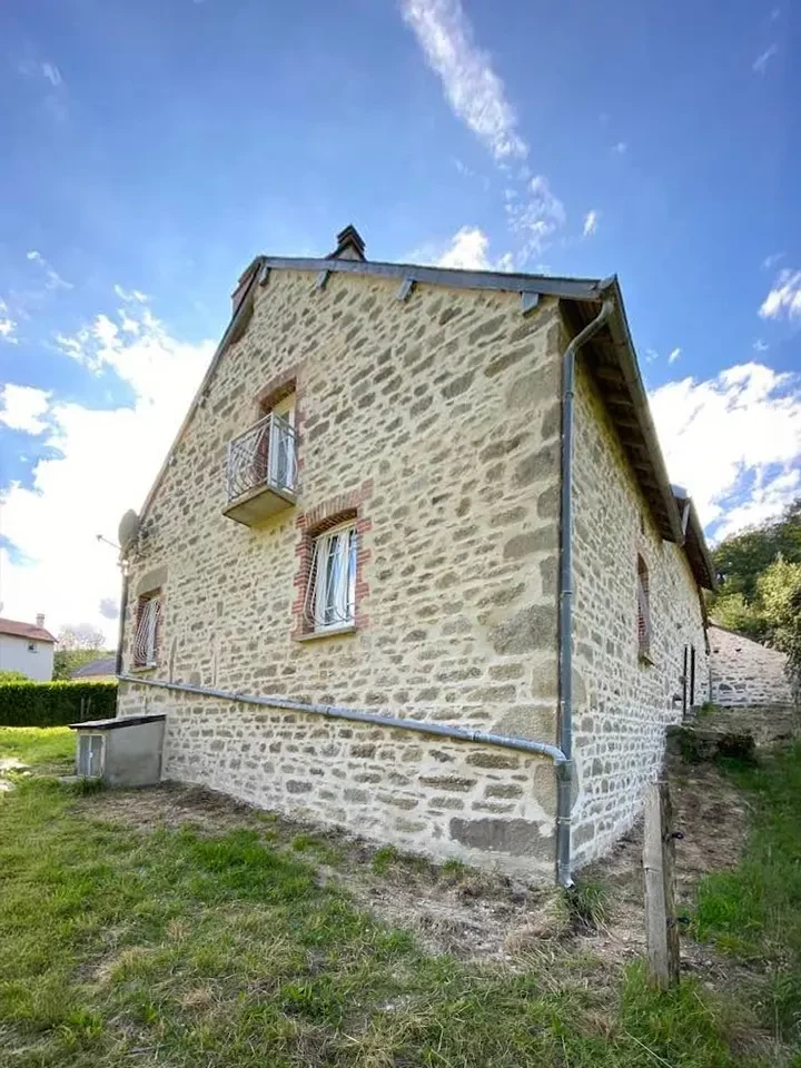 Façade extérieure d'une maison traditionnelle en pierre calcaire avec porte d'entrée verte à panneaux et fenêtre assortie aux volets ouverts