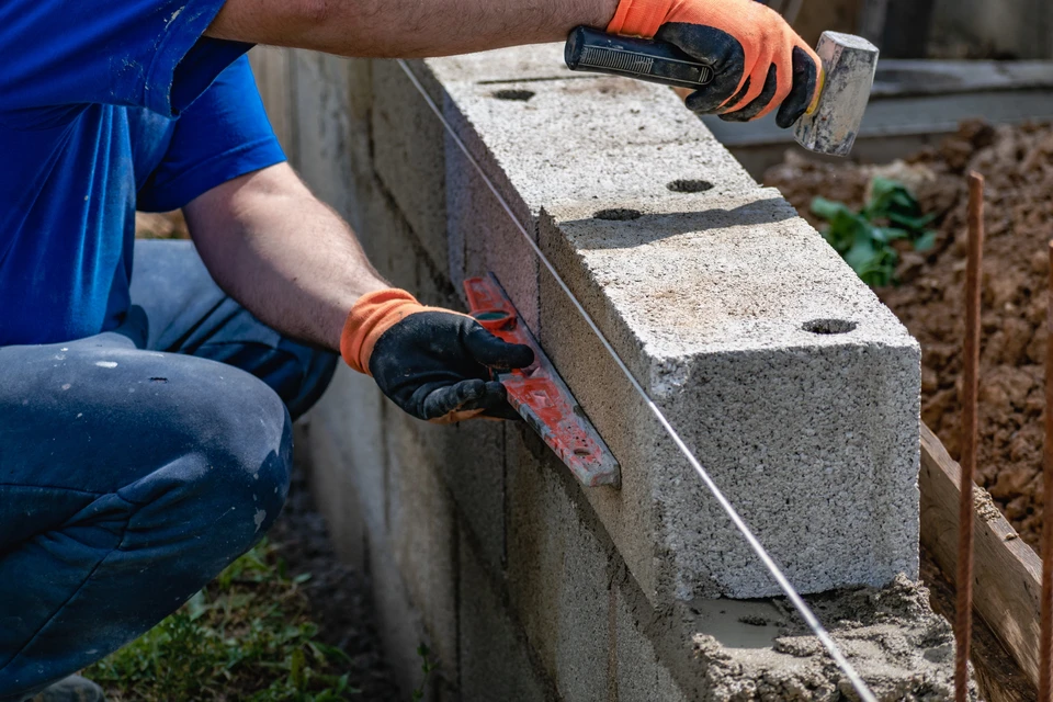 Mur extérieur en briques beiges et grises disposées en appareil anglais