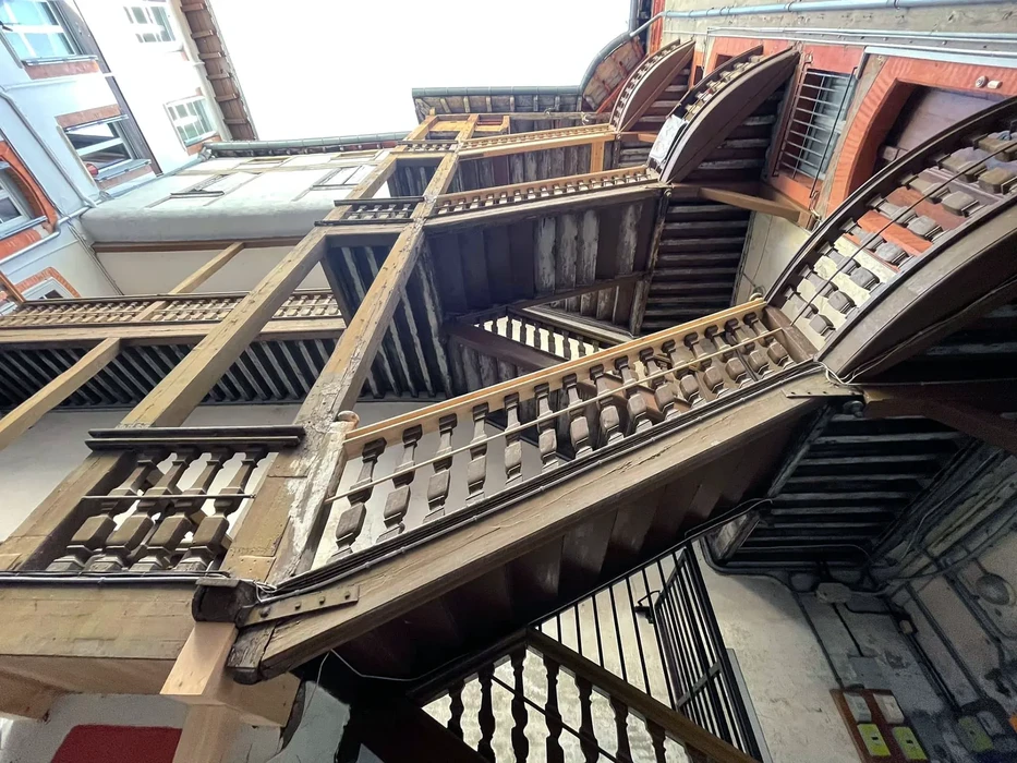 Façade en brique rouge d'un bâtiment historique avec porte d'entrée rouge sous porche en pierre